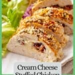 Sliced cream cheese stuffed chicken breast on a plate alongside a salad with a border and text around the photo.