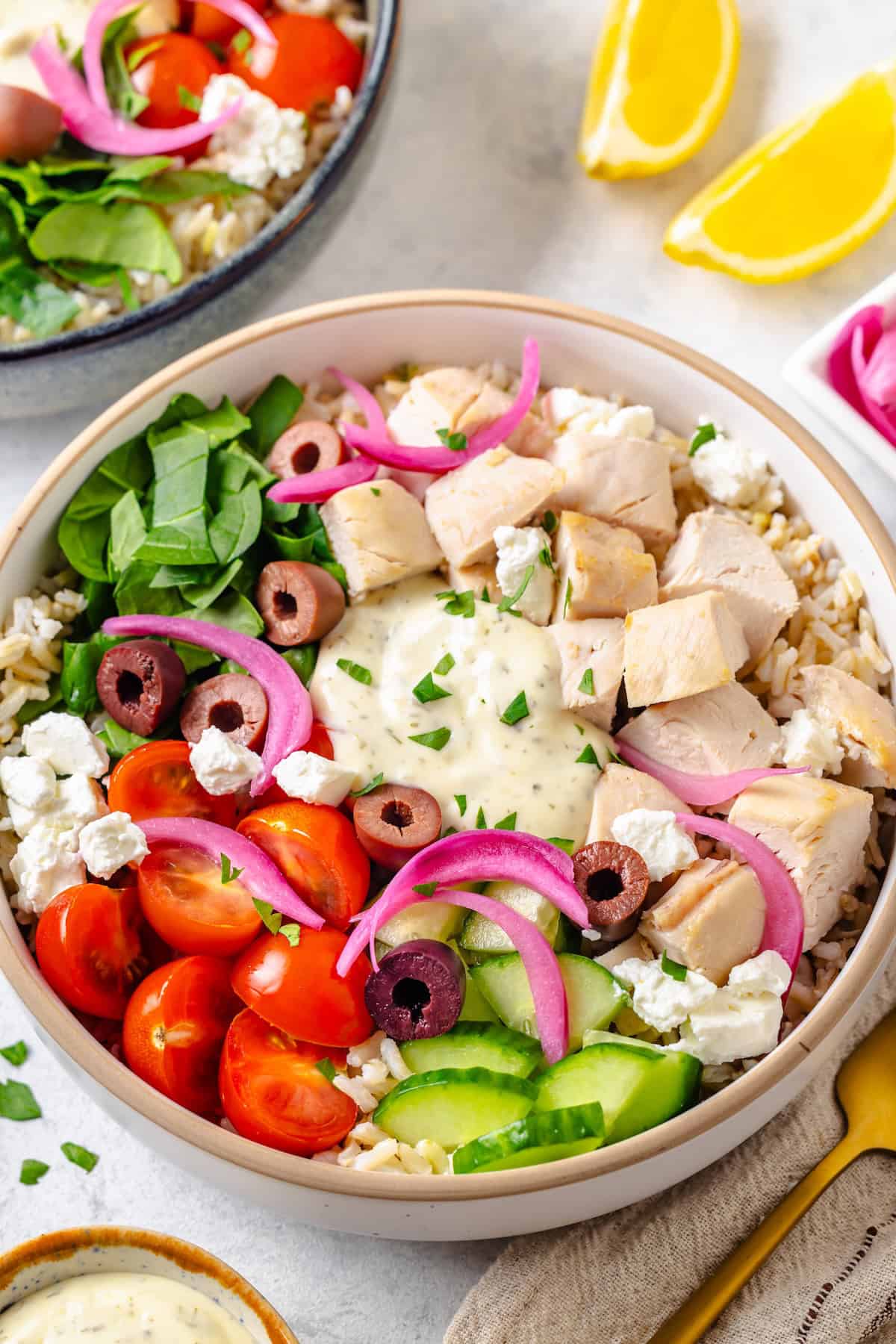 A colorful Greek chicken bowl with rice and veggies.