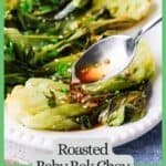 Honey garlic sauce being drizzled over roasted bok choy on a white serving platter with a green border and text around the photo.