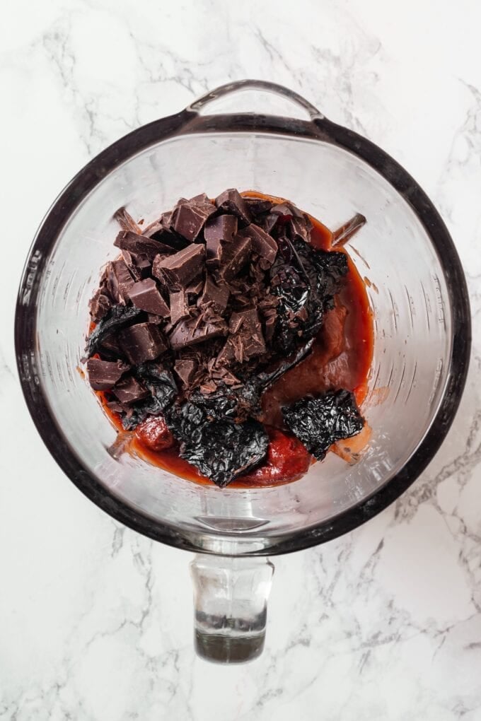 A glass measuring cup with tomatoes, peppers and chopped chocolate.