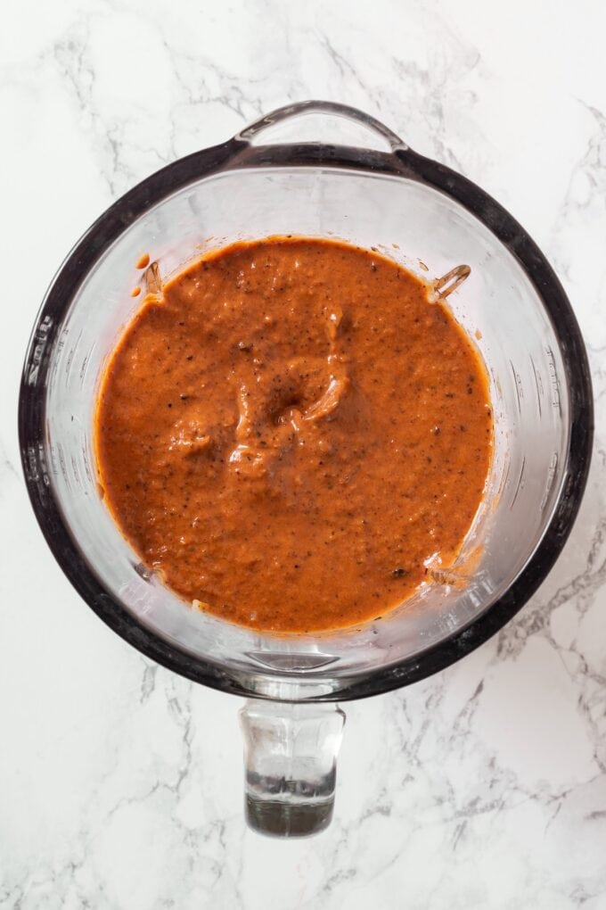 A blended mole sauce in a glass measuring cup.
