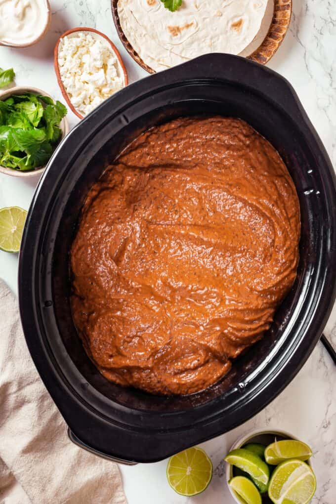 A smooth mole sauce over chicken thighs in a slow cooker.