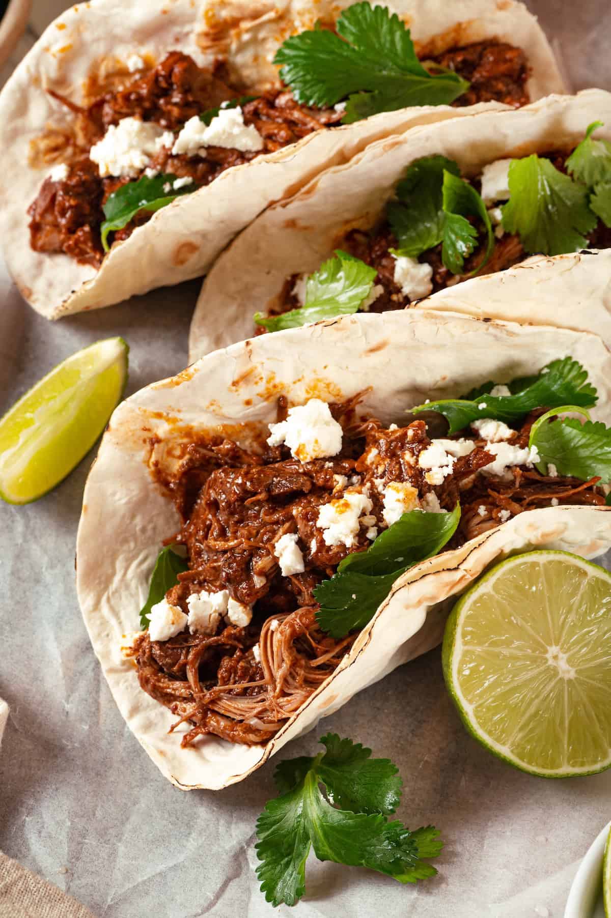 Mole chicken tacos in flour tortillas with queso fresca and cilantro on top.