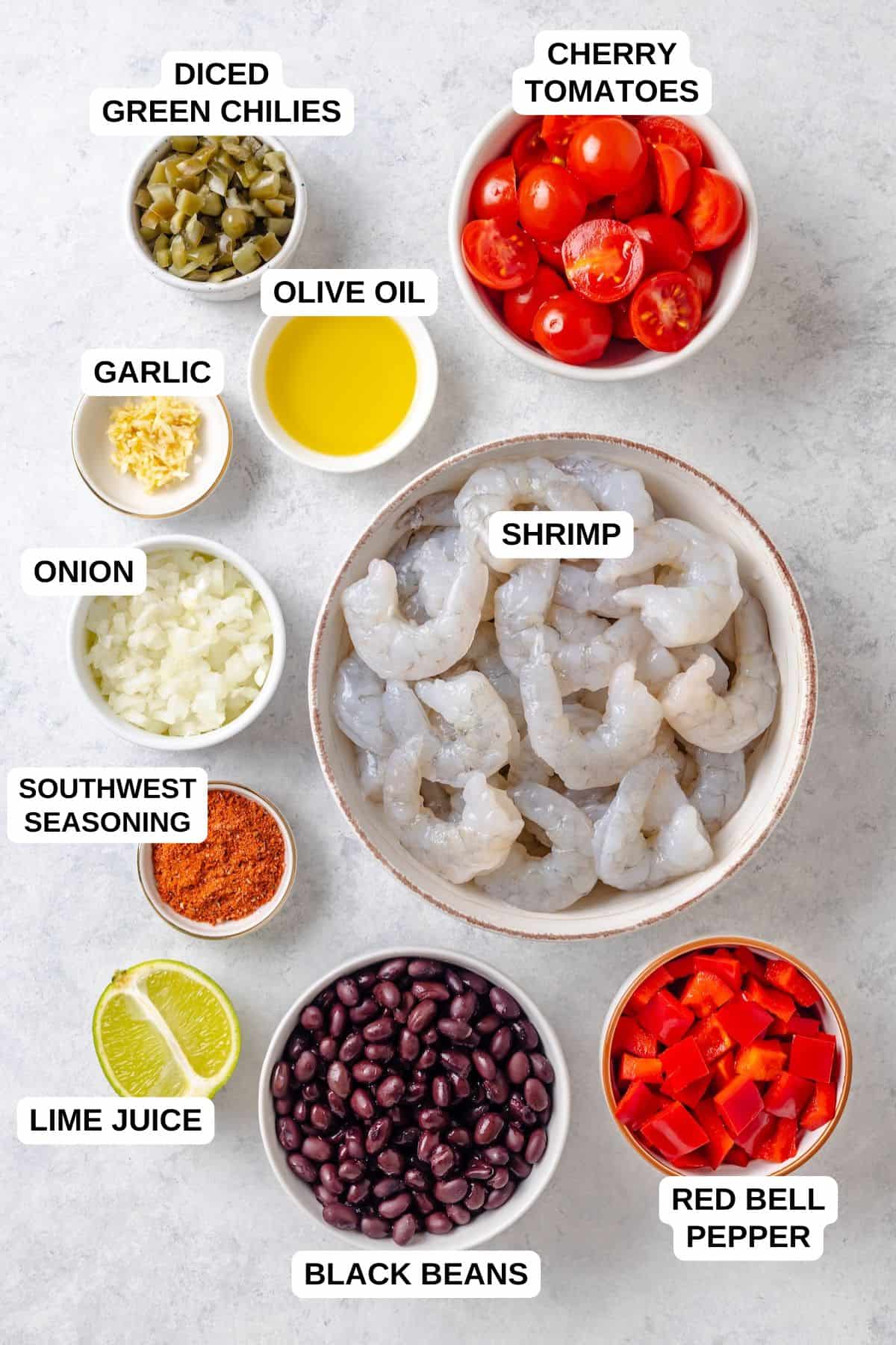 Ingredients laid out in separate bowls for making a shrimp recipe with black beans, tomatoes, peppers and diced green chilies.