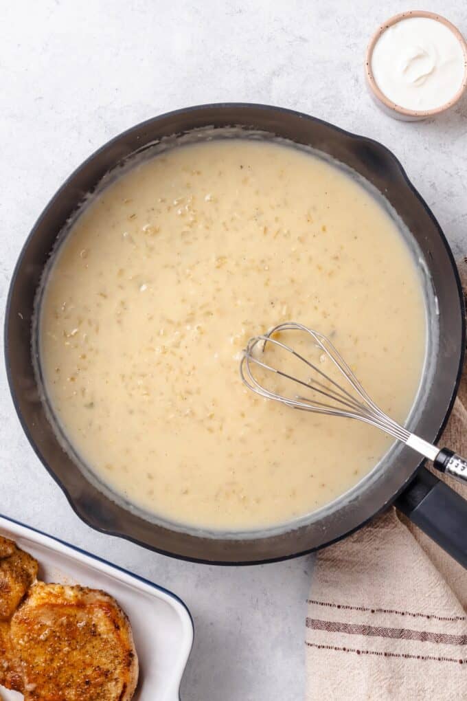 A gravy being whisked together in a large dark skillet.