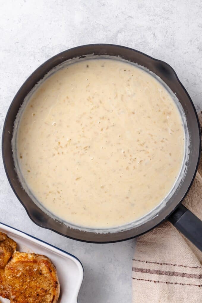 A creamy onion gravy in a large skillet.