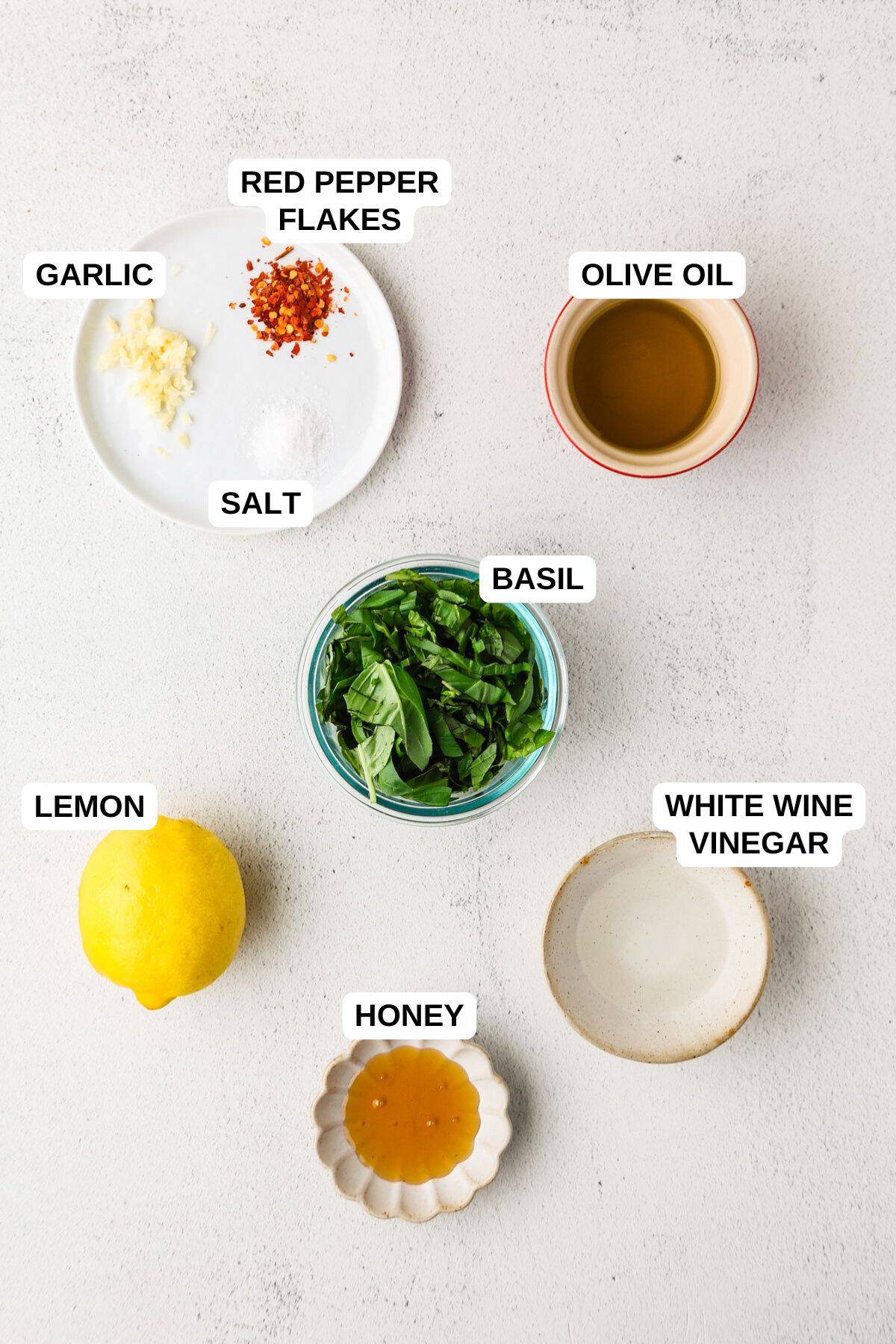 Ingredients laid out in separate bowls from making a lemon basil dressing.