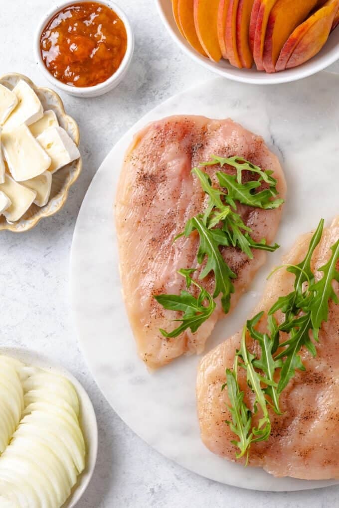 Butterflied chicken breasts seasoned with salt and pepper and layered with fresh arugula.