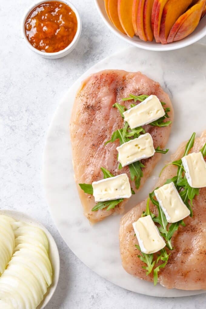 Butterflied chicken breasts seasoned with salt and pepper and layered with fresh arugula and small slices of brie cheese.