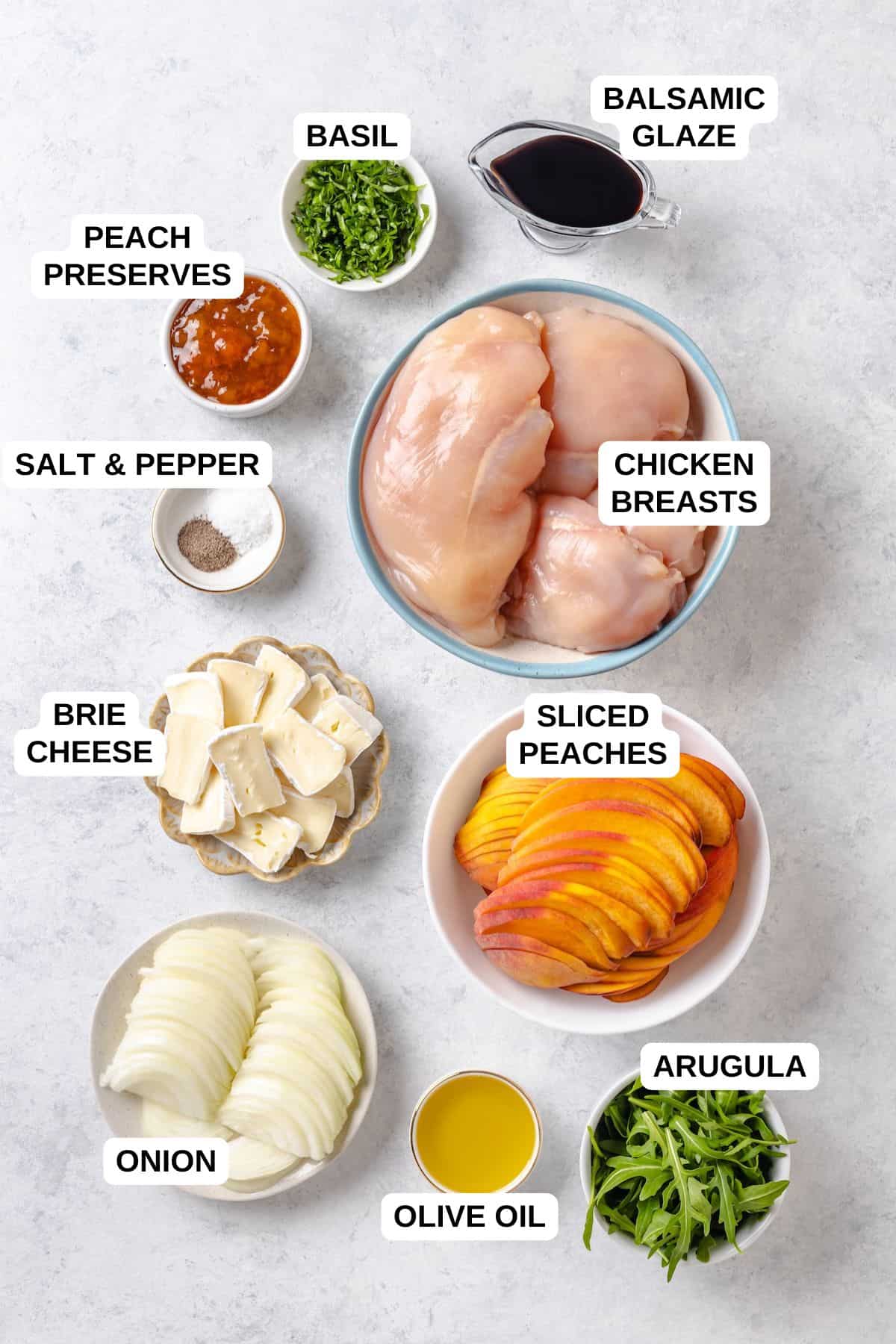 Ingredients laid out in separate bowls for making a peach chicken recipe with brie cheese, onion and basil.
