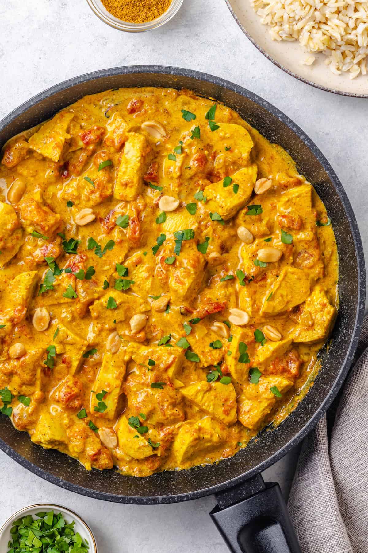 Quick one pan chicken curry in a large skillet with peanuts and cilantro sprinkled on top.