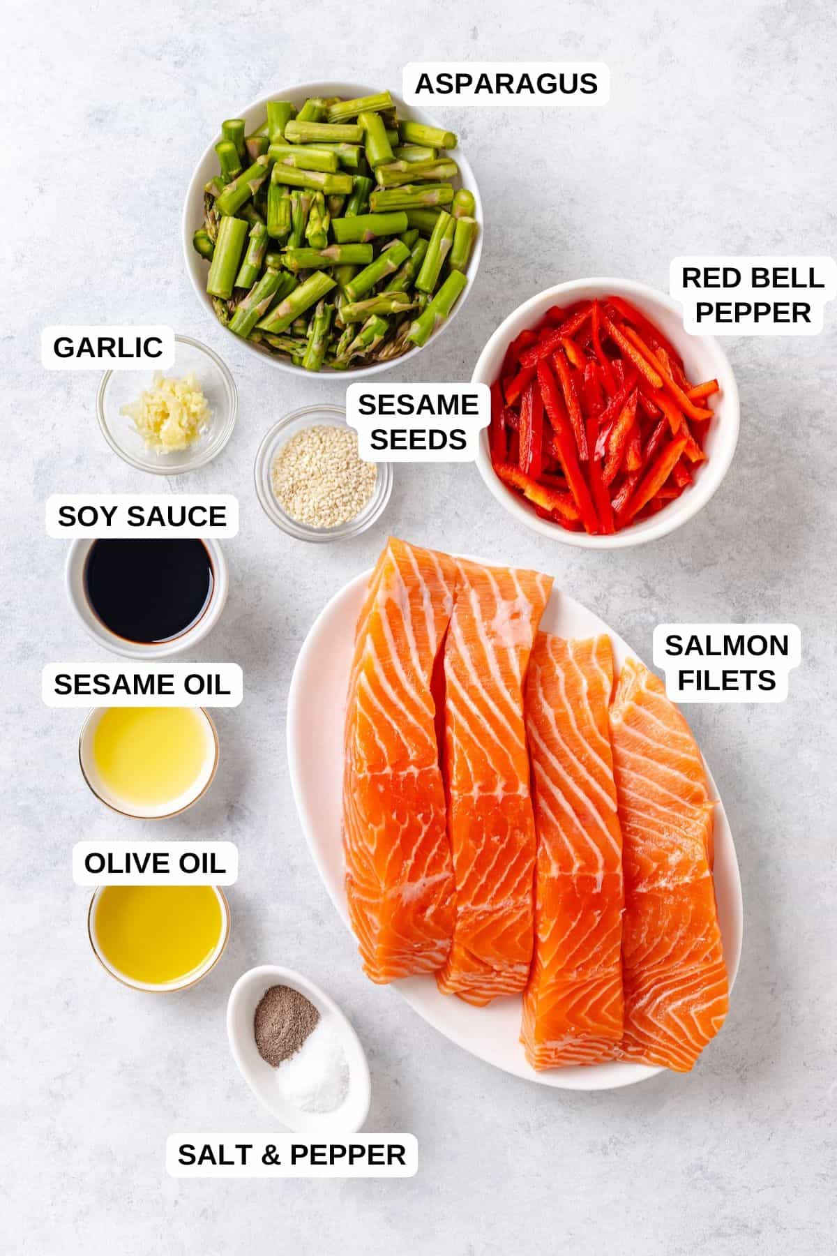 Ingredients laid out in separate bowls for making a salmon and asparagus recipe with bell peppers, soy sauce and sesame seeds.