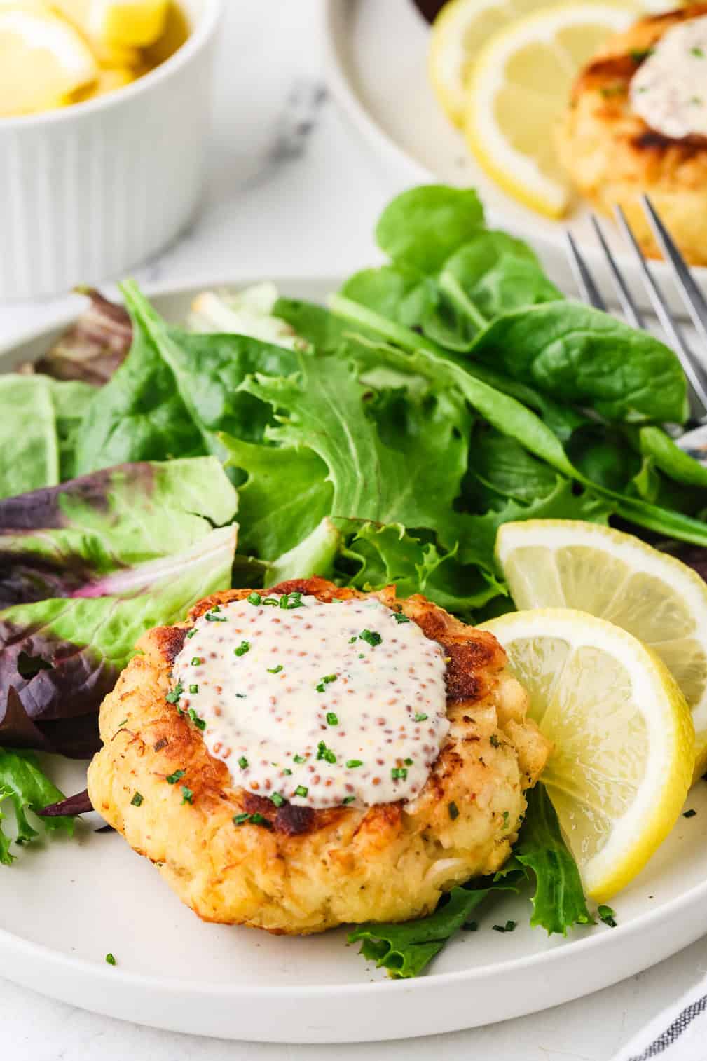 A crab cake with mustard remoulade on top sprinkled with finely chopped chives.