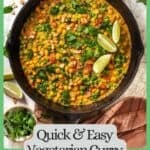 A cast iron pan with a vegetarian curry with chickpeas, spinach, tomatoes and peas with cilantro and lime wedges on top and a green border and text around the photo.