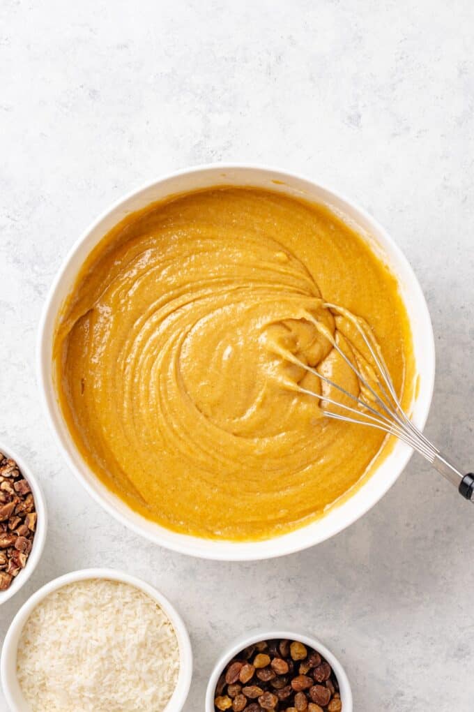 A sweet bread batter being whisked together in a white bowl before the add-ins are mixed in.
