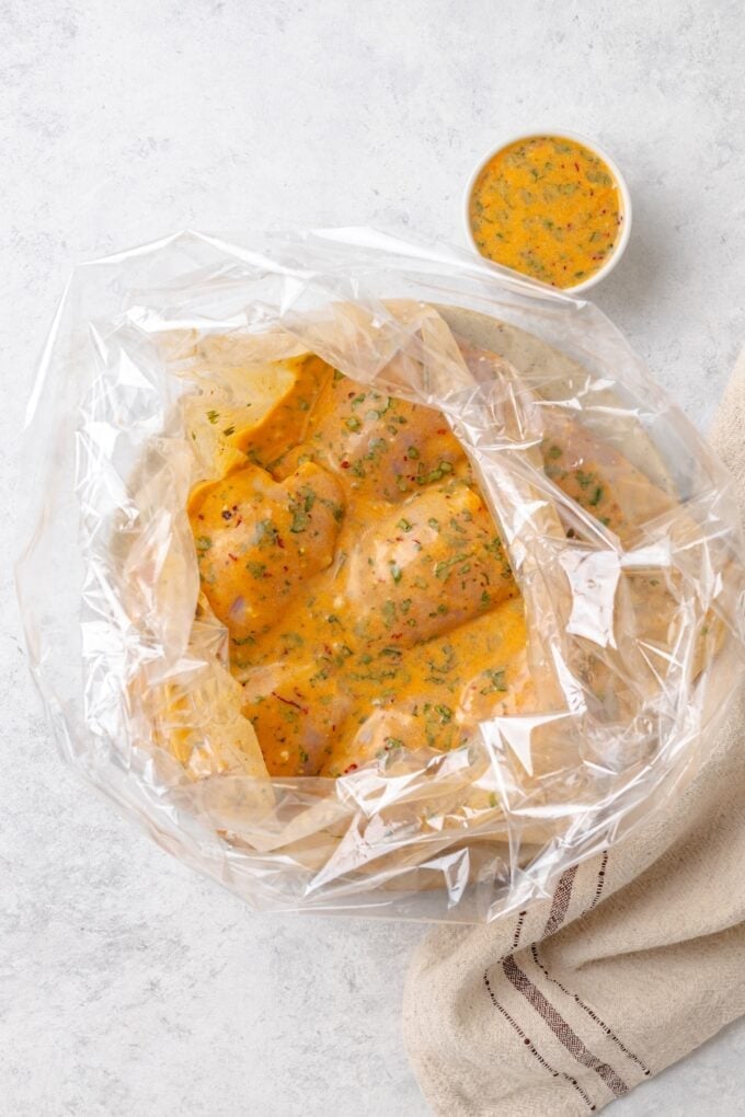 Chicken thighs in a plastic bag being marinated in a coconut lime mixture.