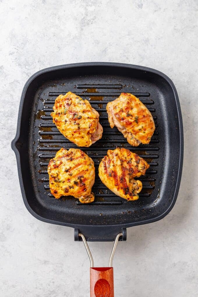 Chicken thighs being cooked on a grill.