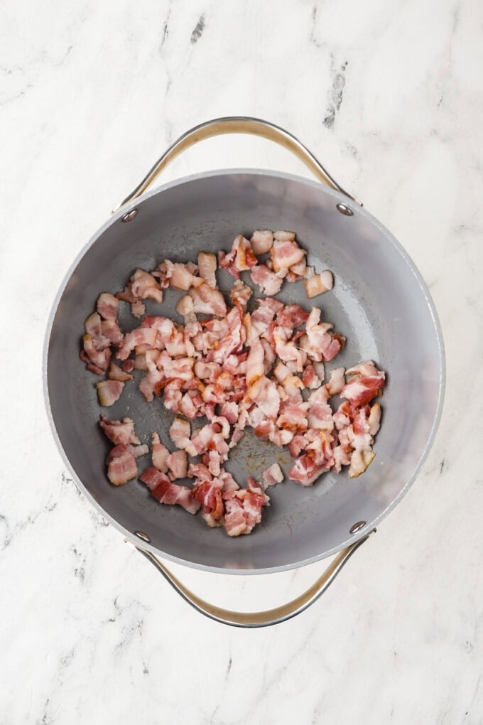 Bacon pieces being cooked in a skillet.