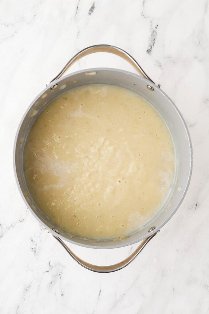 Mostly pureed potatoes being cooked in a pot to make corn chowder.