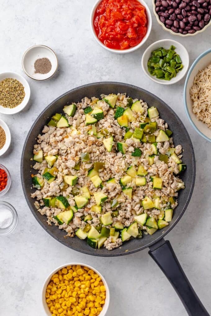 A large skillet with cooked ground turkey mixed with onion and zucchini.