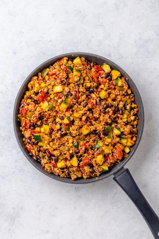 A large skillet with ground turkey, rice, beans and veggies all cooked together.