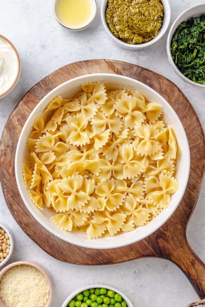 Cooked bow tie pasta in a bowl set on a cutting board.
