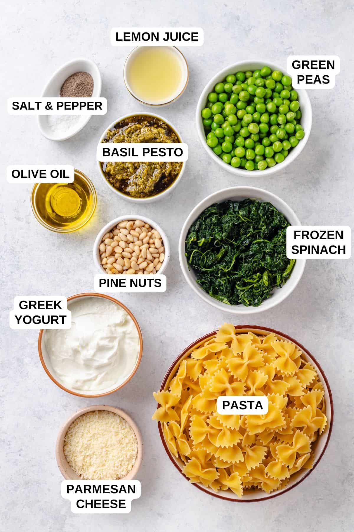 Ingredients in separate bowls for making a pasta dish with spinach, peas and pesto.