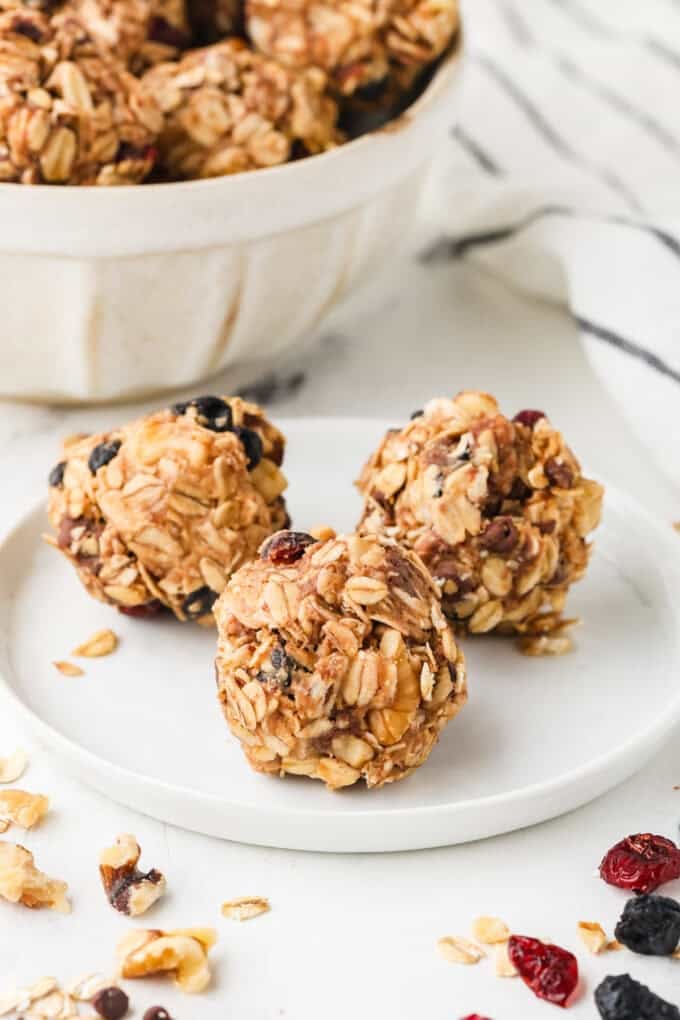 Three oat and dried fruit energy bites on a white plate.