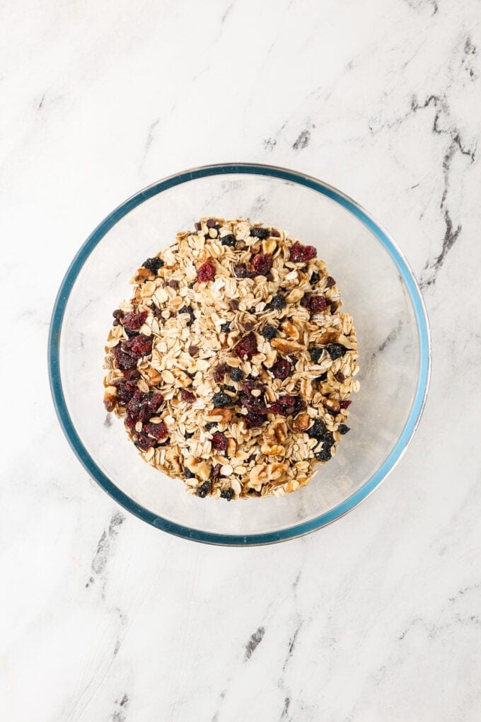 A clear glass bowl with a mixture of rolled oats and dried fruit and walnuts.