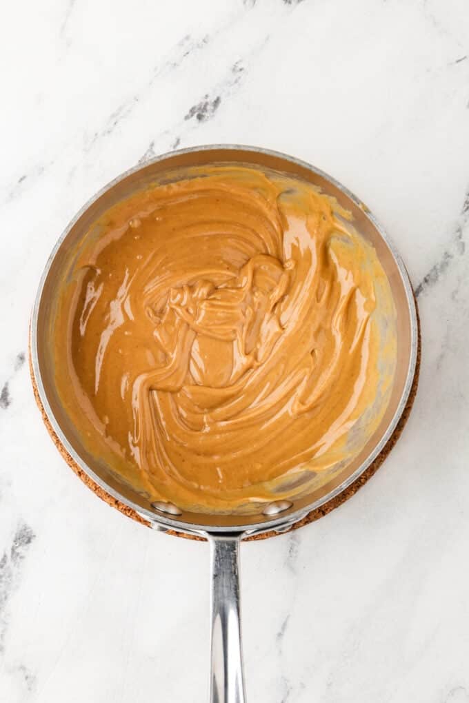 A creamy peanut butter and honey mixture in a small sauce pan.