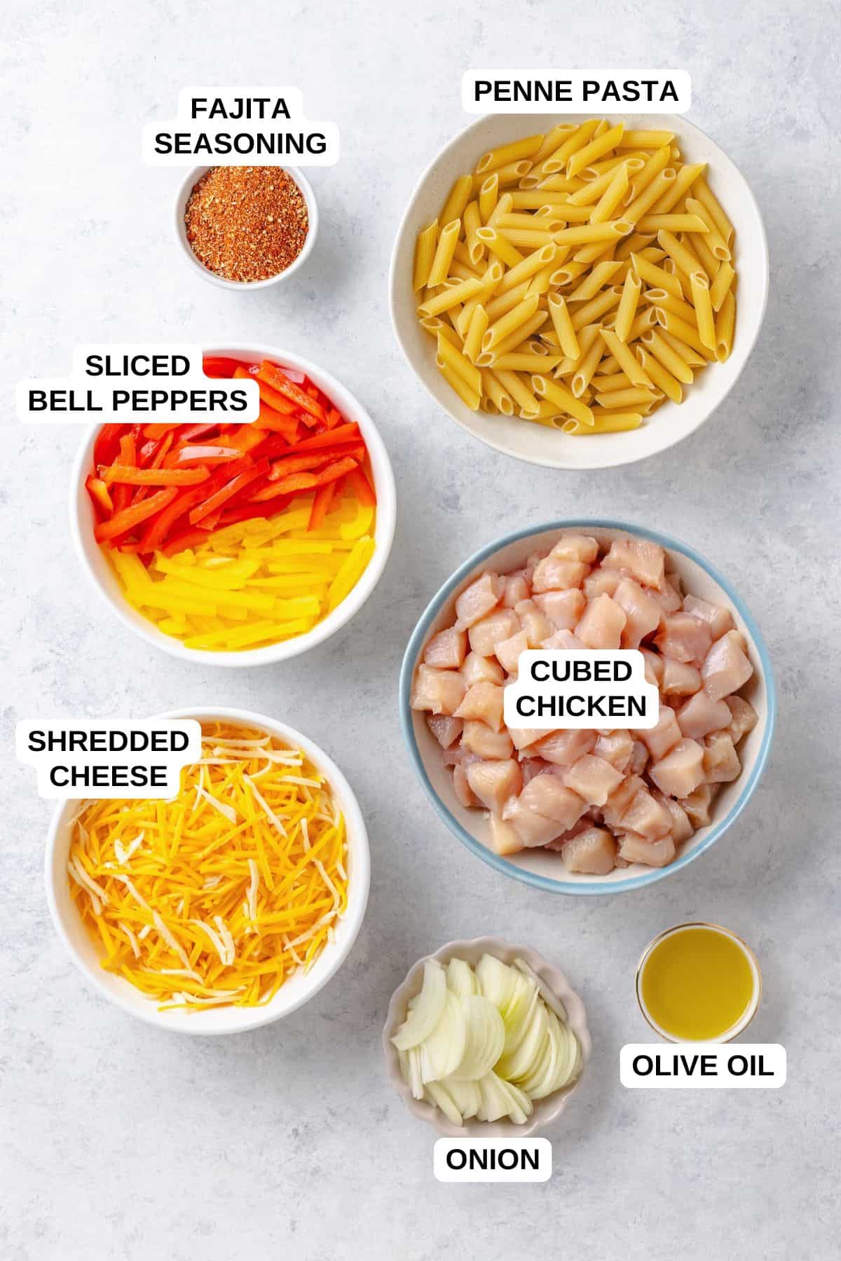 Ingredients laid out in separate bowls for making a fajita chicken pasta recipe with peppers and onions.