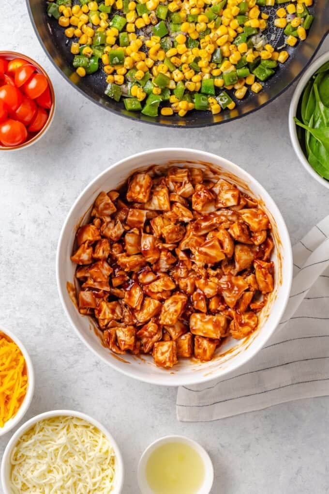 A white bowl of cubed cooked chicken pieces mixed with BBQ sauce.