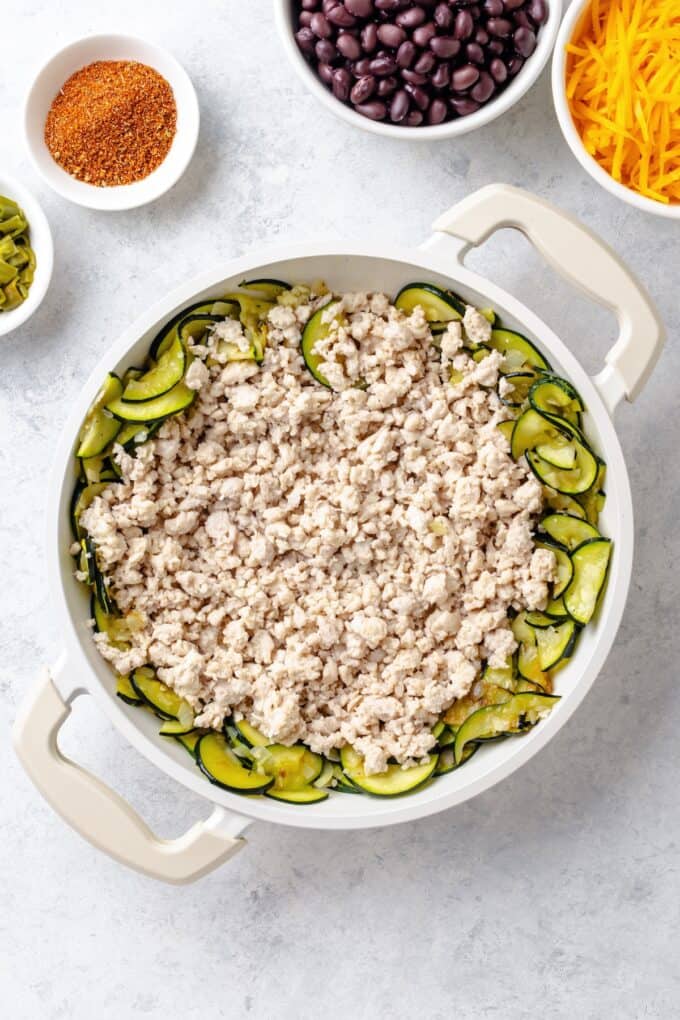 Cooked ground turkey in a skillet with sautéed zucchini.