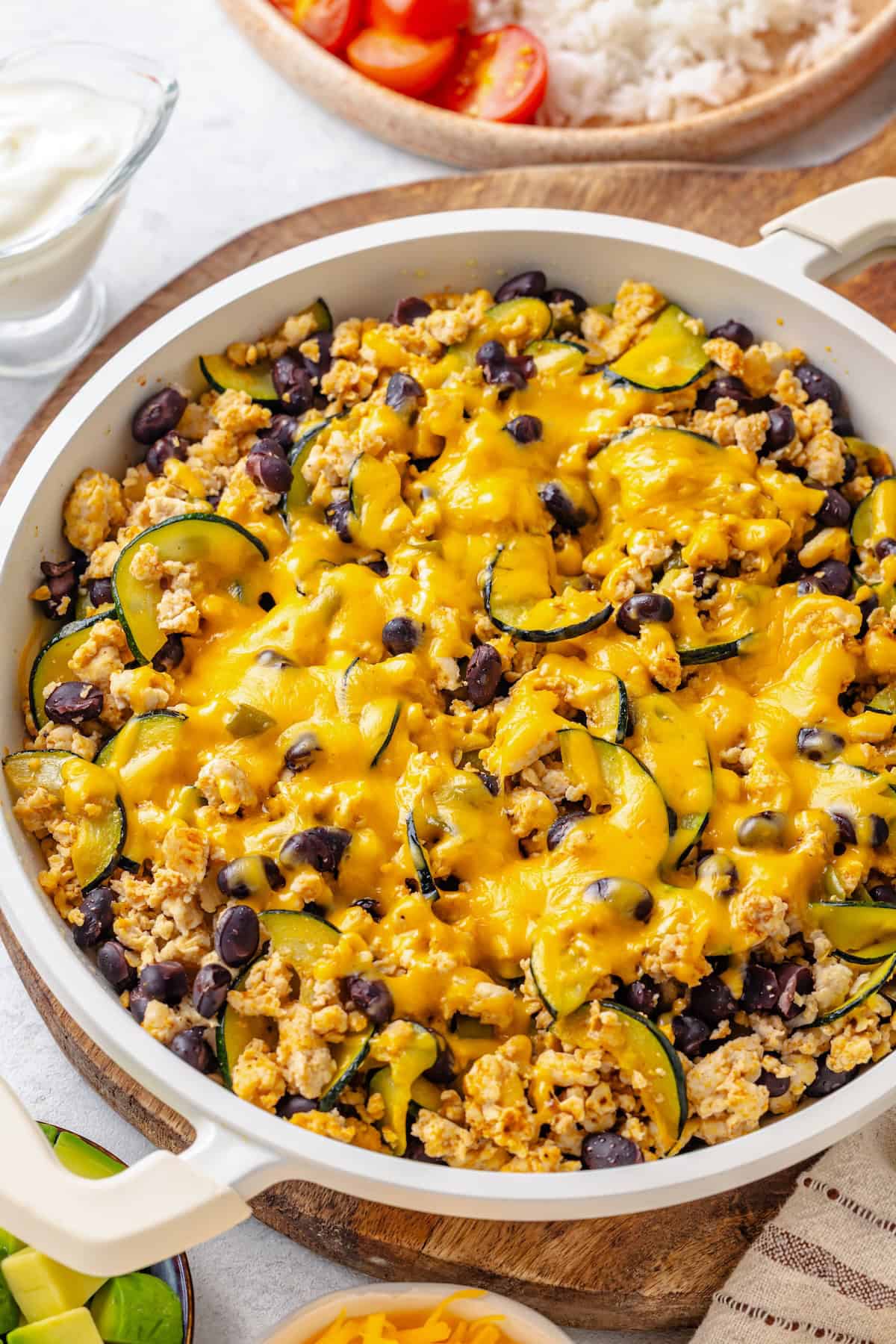 A ground turkey skillet with zucchini and black beans and melted cheese on top.
