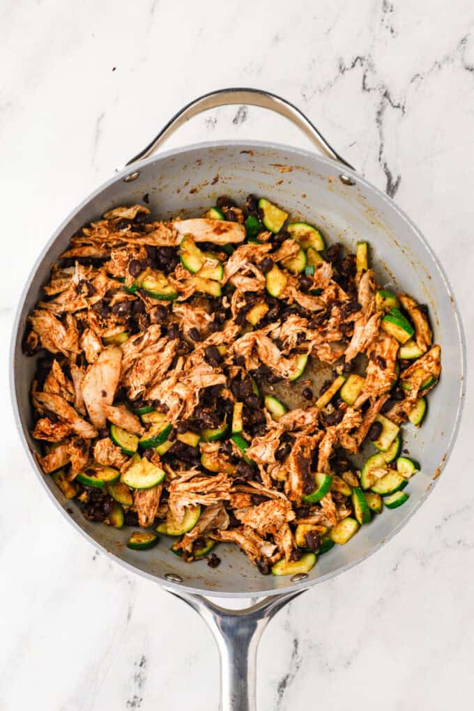 A skillet with a chicken, black bean and zucchini mixture.