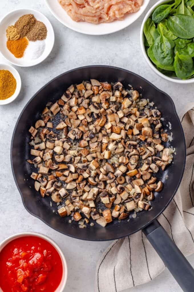 Sautéed mushrooms and onion and garlic in a large dark skillet.