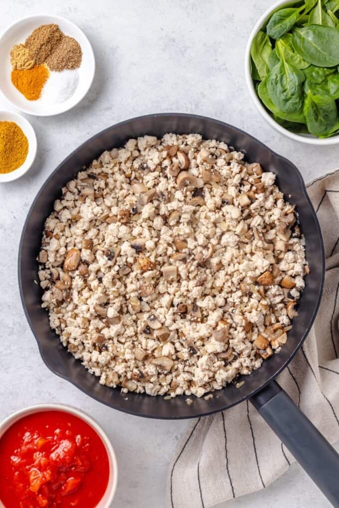 Cooked ground chicken with mushrooms and onions in a large dark skillet.