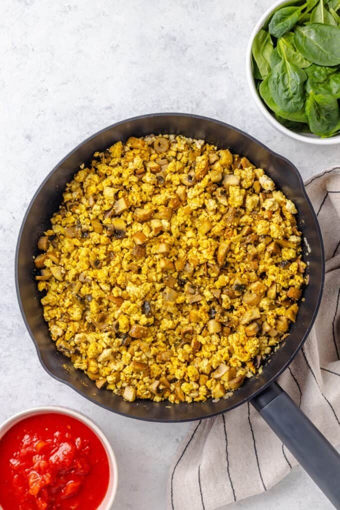Curry spices added to a ground chicken and mushroom mixture in a large dark skillet.