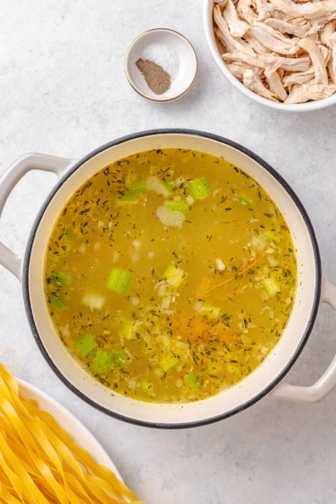 A large soup pot with sautéed onions, carrots, celery and garlic in it plus broth and seasonings.