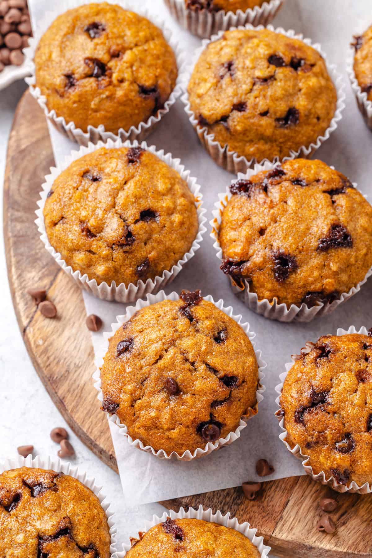 Healthy chocolate chip muffins set out on a wood cutting board.
