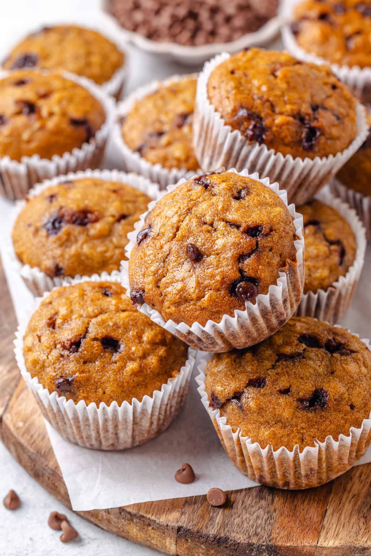 Chocolate chip oatmeal muffins stacked on each other on a wood tray.