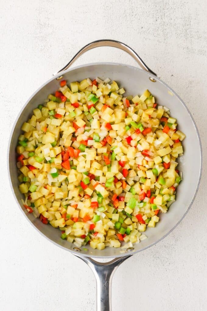 A mixture of diced potatoes and peppers in a large skillet.