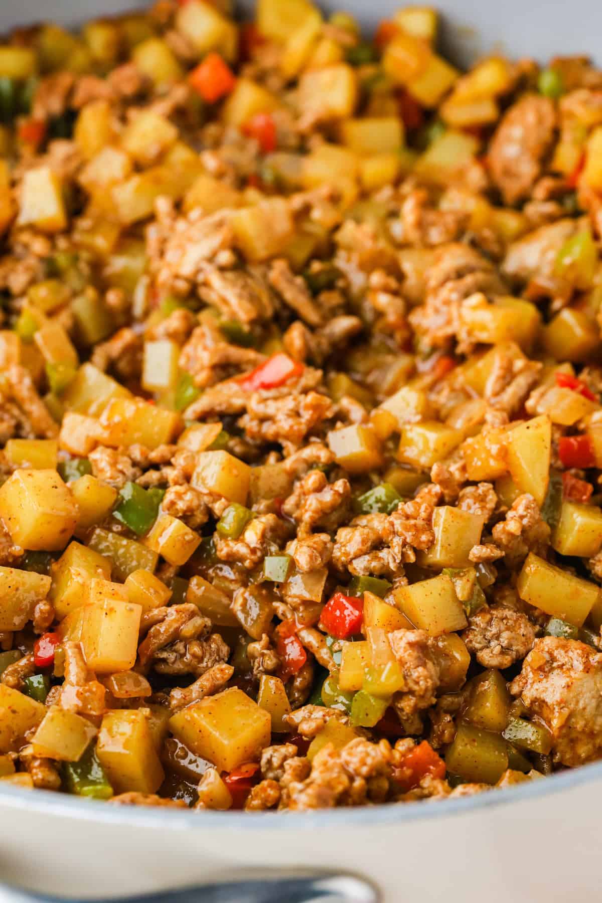 Close up of taco flavored ground turkey with potatoes and peppers in a large skillet.