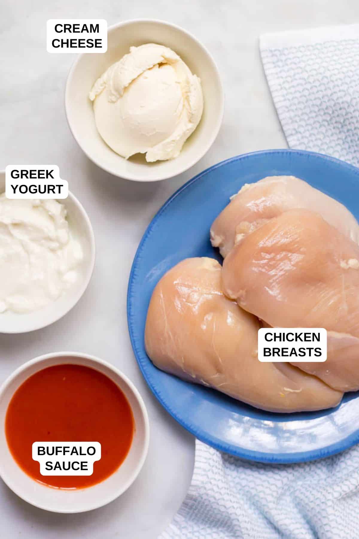 Healthy slow cooker buffalo chicken is lightened up (no butter!), takes just minutes to prep and can be used for sandwiches, sliders, wraps, salads or nachos! | www.familyfoodonthetable.com Ingredients laid out in separate bowls and plates for making a healthy version of a crock pot buffalo chicken recipe.